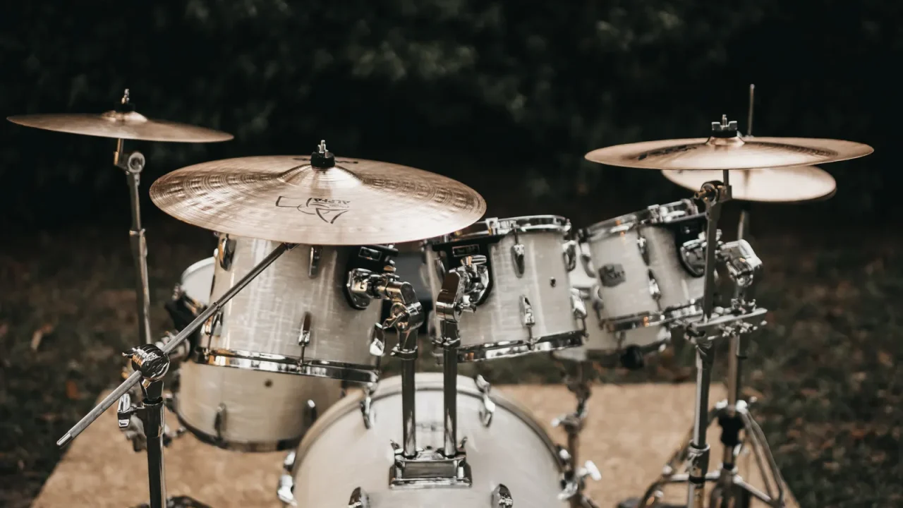 A white acoustic drum kit with cymbals set up outdoors at night