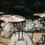 A white acoustic drum kit with cymbals set up outdoors at night