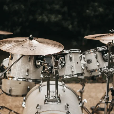 A white acoustic drum kit with cymbals set up outdoors at night