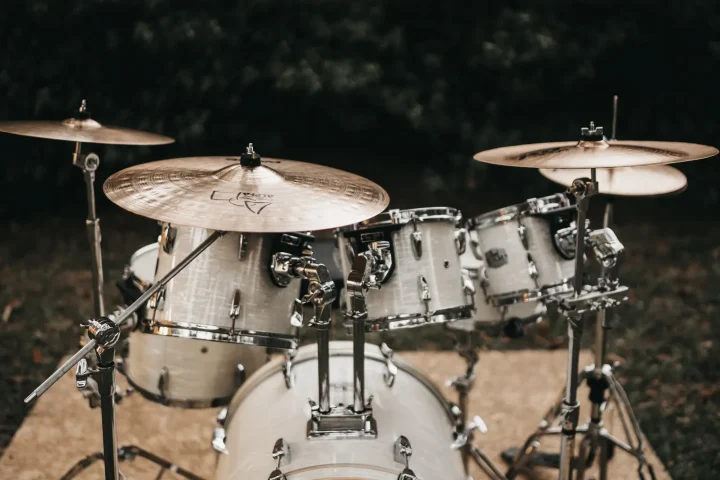 A white acoustic drum kit with cymbals set up outdoors at night