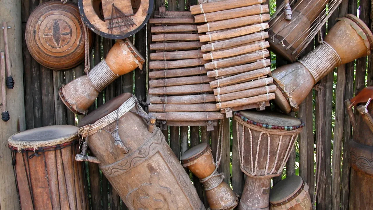 Assorted wooden African percussion instruments, including djembes and a balafon, displayed together