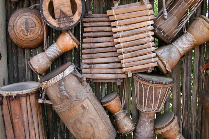 Assorted wooden African percussion instruments, including djembes and a balafon, displayed together