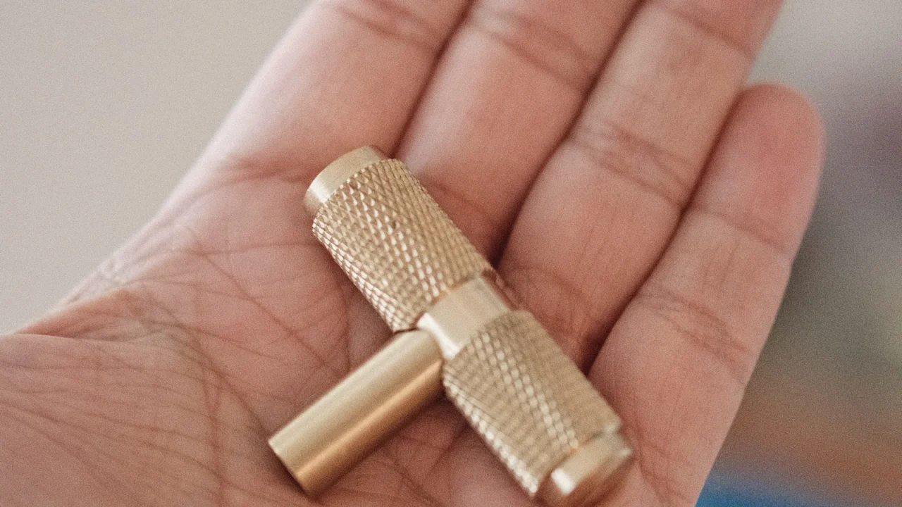 A brass drum key held in an open palm