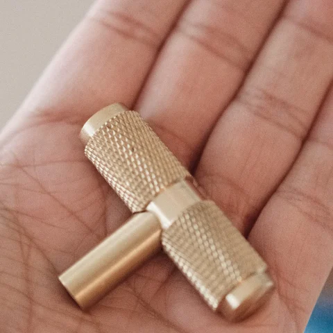 A brass drum key held in an open palm