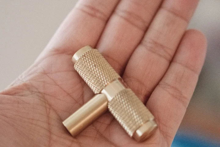 A brass drum key held in an open palm