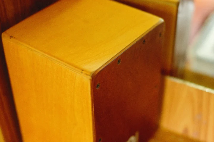 Close-up of a wooden cajon showing its screwed-on front plate