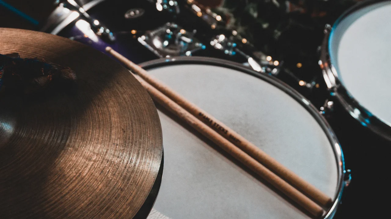 A drumstick resting across a drum next to a cymbal