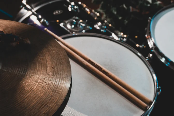 A drumstick resting across a drum next to a cymbal