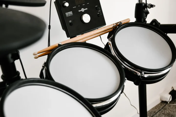 Close-up of drumsticks resting on the mesh pads of an electronic drum kit beside its sound module