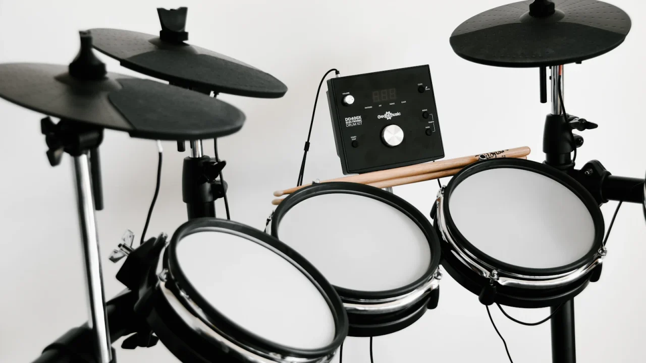 An electronic drum kit with mesh pads, cymbal pads and a sound module against a white wall