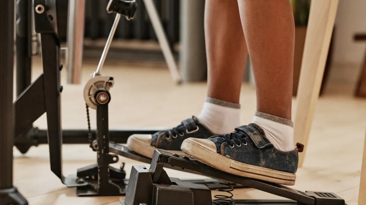 A foot in a sneaker pressing a bass drum pedal