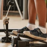 A foot in a sneaker pressing a bass drum pedal