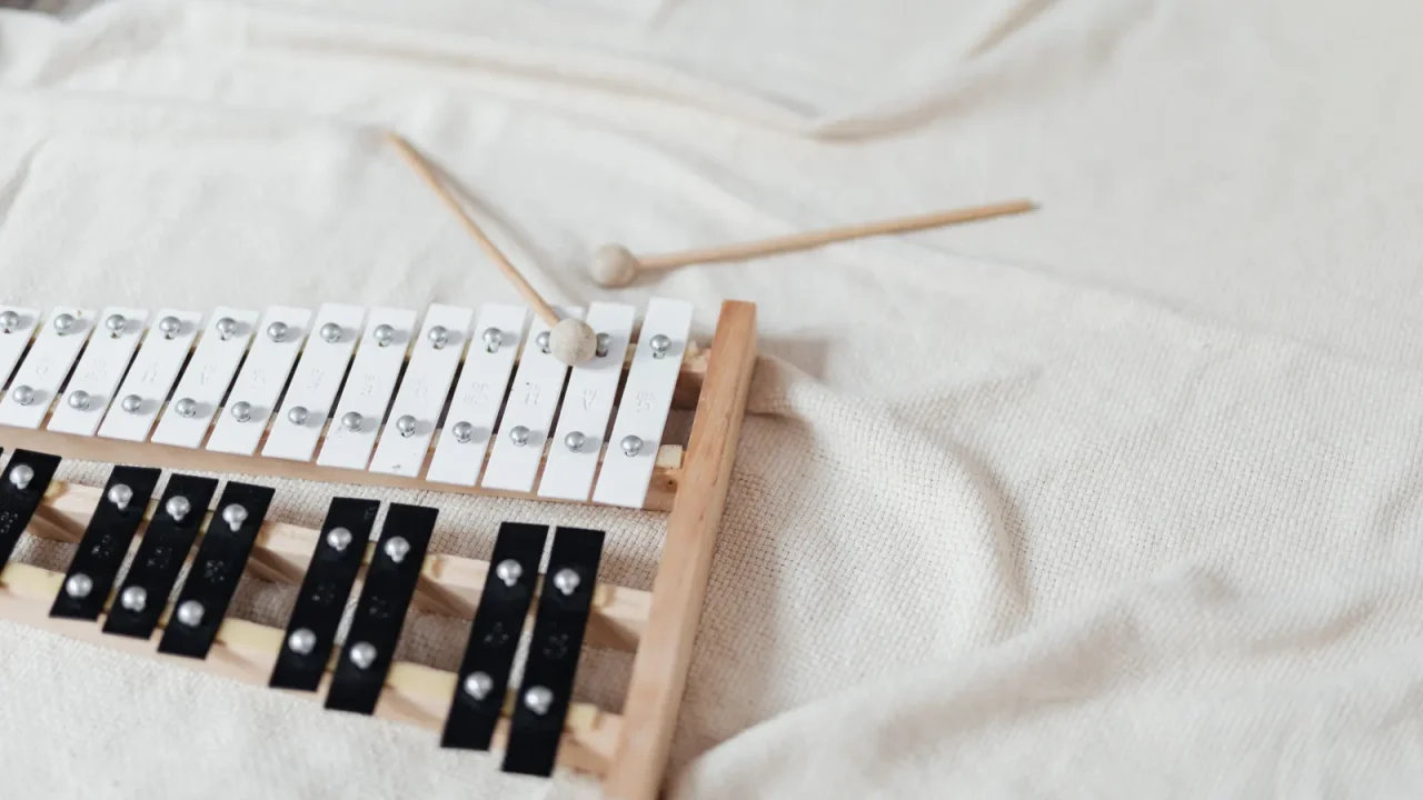 A glockenspiel with two mallets lying on a white blanket