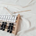 A glockenspiel with two mallets lying on a white blanket