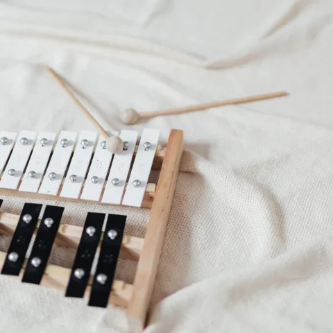 A glockenspiel with two mallets lying on a white blanket