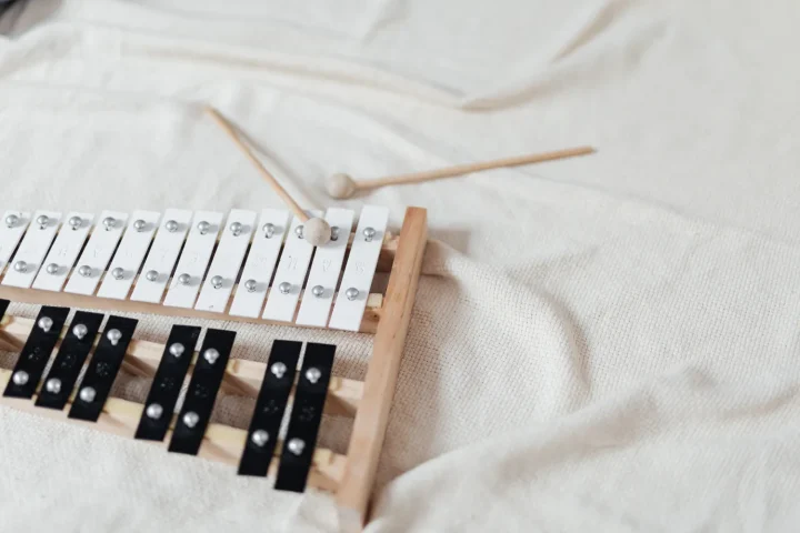 A glockenspiel with two mallets lying on a white blanket