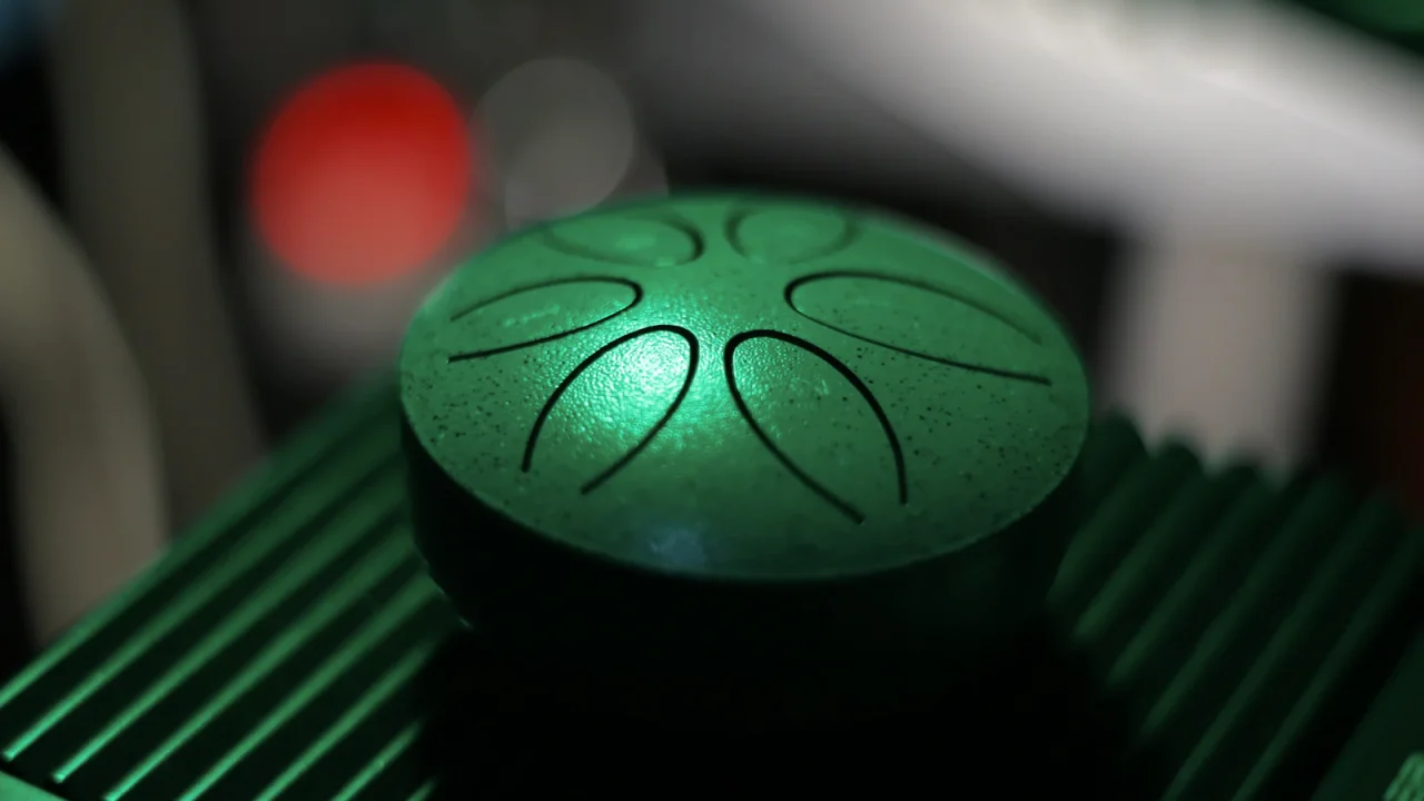 A green steel tongue drum with tongues cut into its top, seen from above