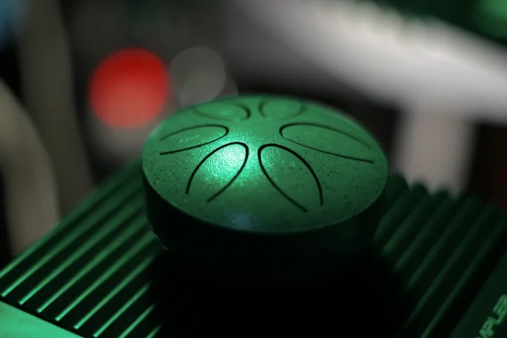 A green steel tongue drum with tongues cut into its top, seen from above