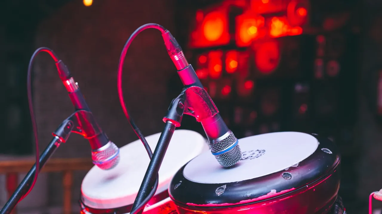 Two hand drums fitted with microphones on a stage under red light