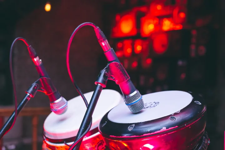 Two hand drums fitted with microphones on a stage under red light