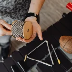 Hands holding a cabasa above a triangle and other small percussion