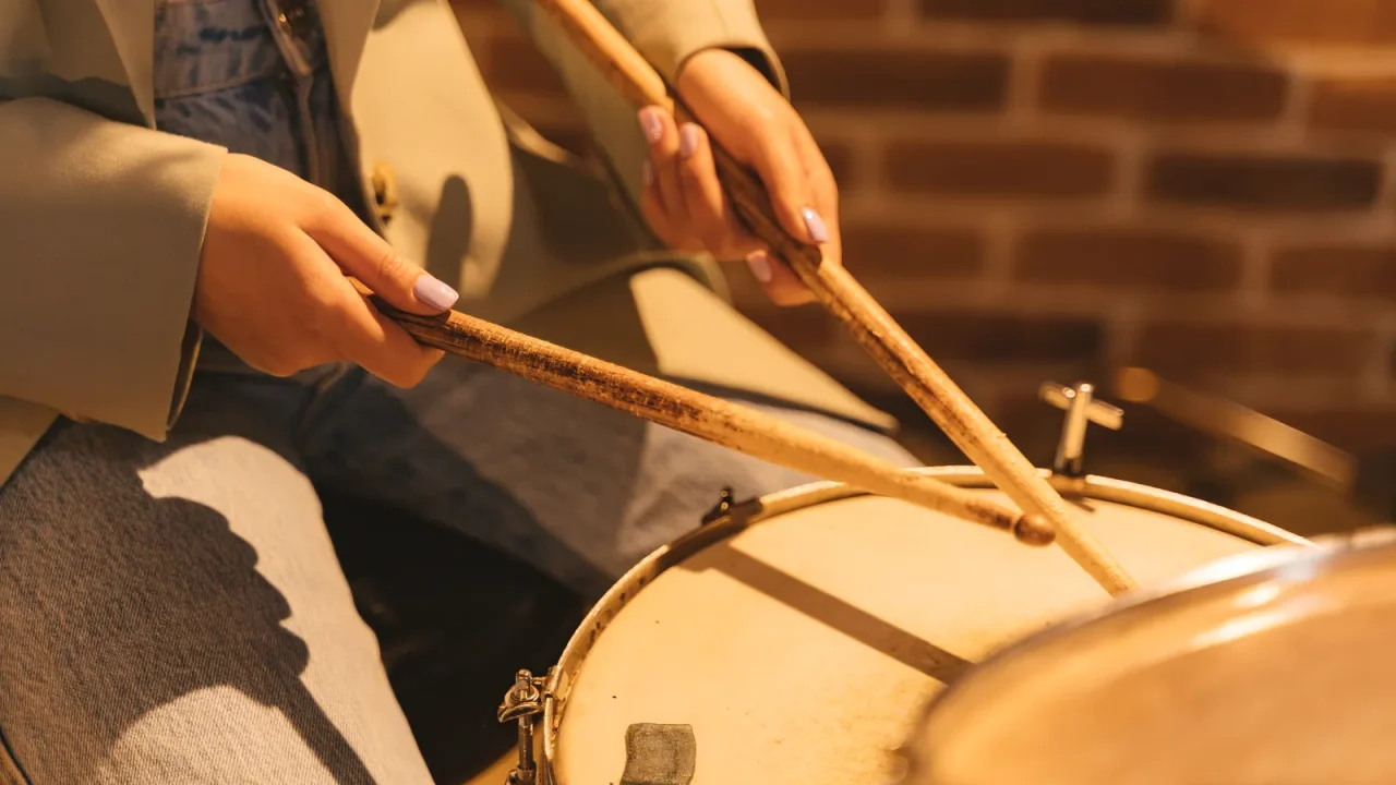 A drummer’s hands holding sticks over a snare drum