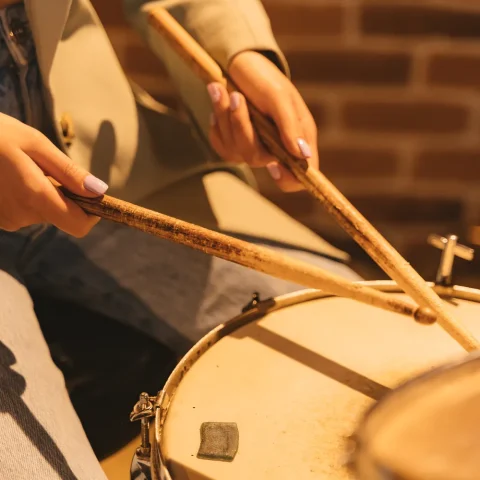 A drummer’s hands holding sticks over a snare drum