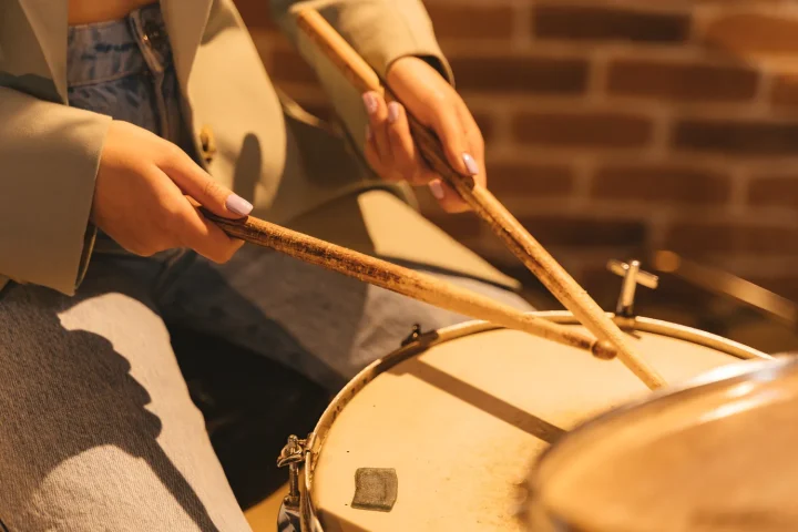 A drummer’s hands holding sticks over a snare drum