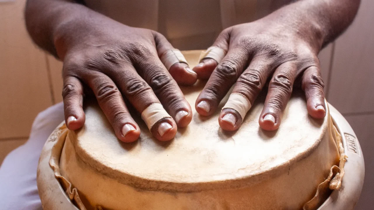Two hands resting on the skin of a djembe