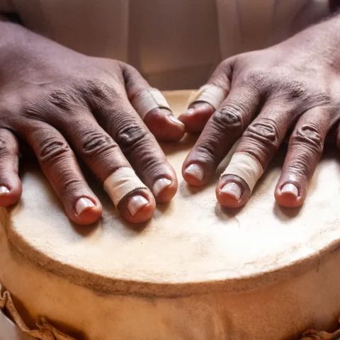 Two hands resting on the skin of a djembe