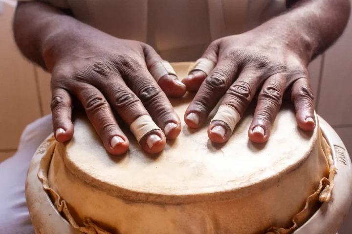 Two hands resting on the skin of a djembe