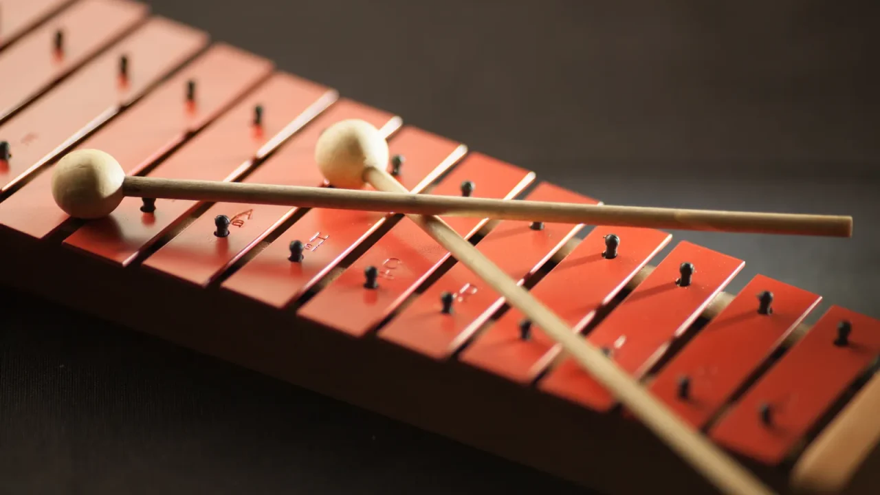 Two mallets resting on the red bars of a xylophone