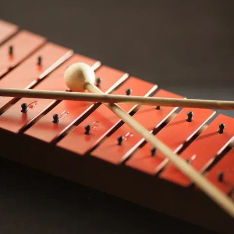 Two mallets resting on the red bars of a xylophone