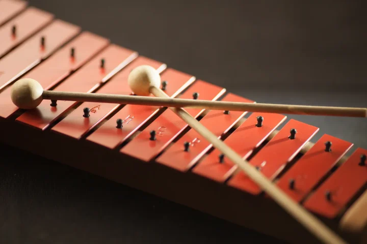 Two mallets resting on the red bars of a xylophone