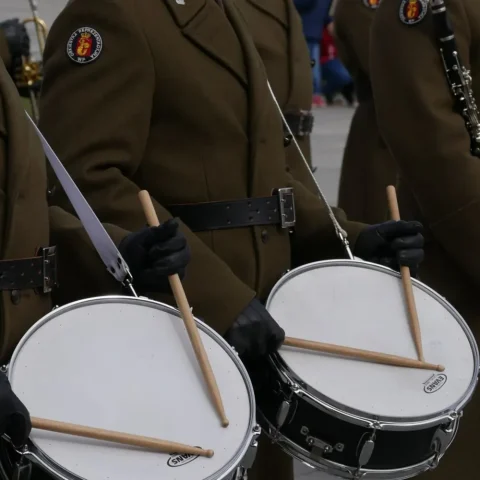 Uniformed marching drummers playing snare drums with gloved hands