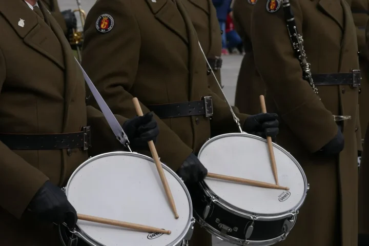 Uniformed marching drummers playing snare drums with gloved hands