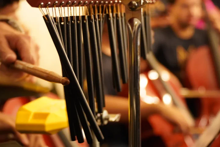 A percussionist striking orchestral chimes during a rehearsal