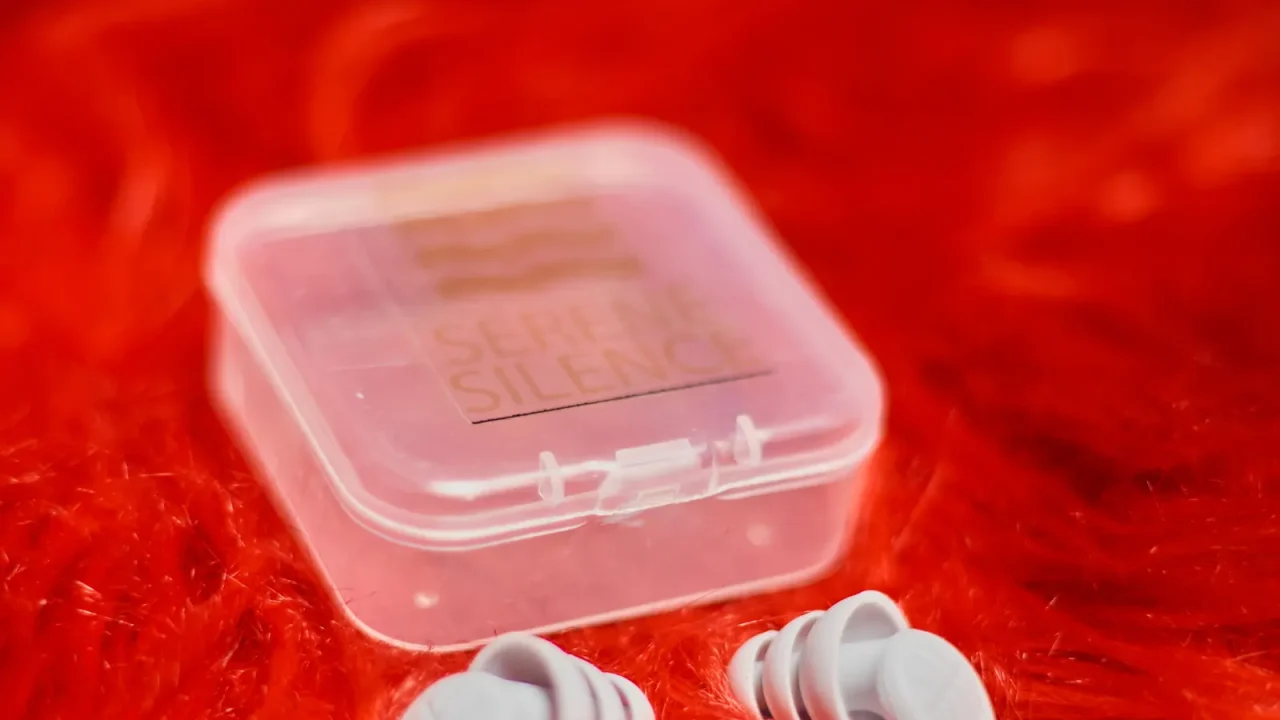 Reusable silicone earplugs beside a small clear carrying case