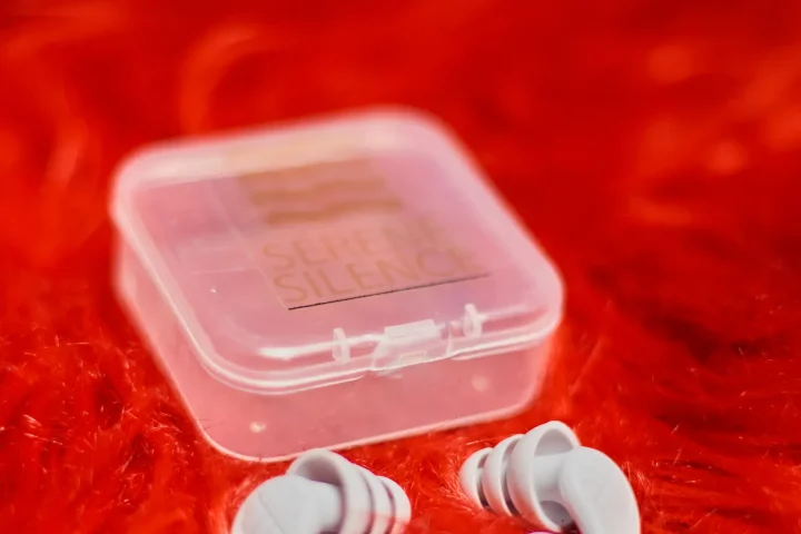 Reusable silicone earplugs beside a small clear carrying case