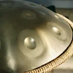 Close-up of a steel handpan showing its hammered tone fields and woven rim