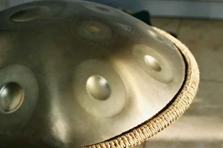 Close-up of a steel handpan showing its hammered tone fields and woven rim